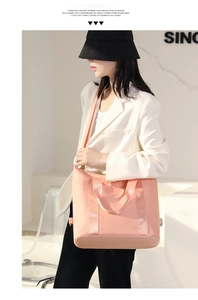 Detail of a large pink nylon tote bag with dual handles and adjustable shoulder strap
