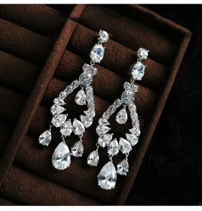 Detail view of silver teardrop earrings with zircon stones in a plush brown velvet box