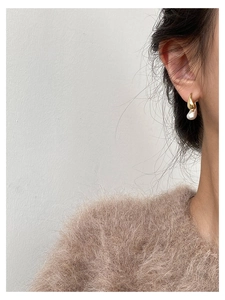 Detailed view of bicolor teardrop earrings featuring gold finish and white pearl inlay