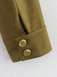 Detailed macro view of olive brown twill jacket cuffs with two yellow resin buttons