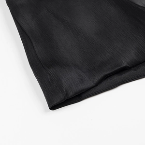 Detailed close-up of pleated black fabric texture and ruffled hemline on a mini dress