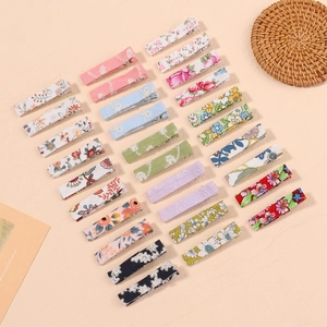 Flat lay detail showing 24 floral and solid color embroidered fabric hair clips for kids