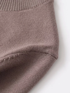 Dettaglio dell'abito midi in maglia color caffè con finiture a coste e cuciture