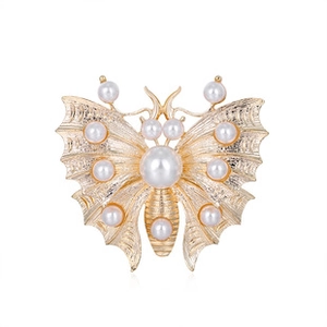 Detail shot of a golden butterfly brooch featuring elegant inlaid pearls on a white background