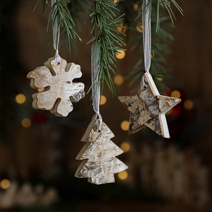 Nordic wooden snowflake and star ornaments hanging on pine branches with warm festive lighting