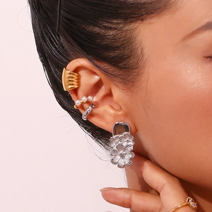 Close-up of layered silver floral earrings with pearl ear cuffs on a model