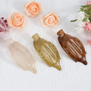 Flat lay of oval duckbill hair clips in beige, green, and brown on white lace