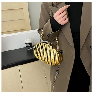 Detail of golden acrylic evening bag with vertical pleated texture and beaded handle