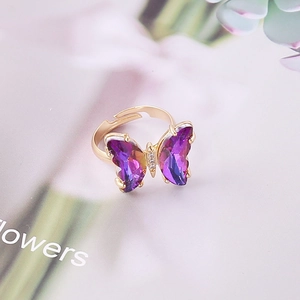 Detalle de anillo de mariposa con cristal degradado púrpura y acabado dorado