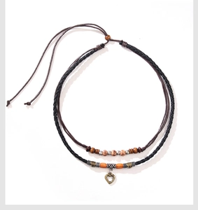 Detail of double-layer necklace with wooden beads and bronze heart pendant on ropes