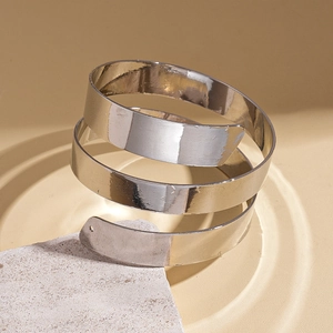 Macro shot of a silver polished spiral metal arm cuff on a minimalist stone display