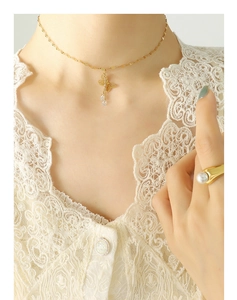 Detail of gold butterfly necklace and pearl ring on model with white lace dress