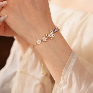 Detailansicht eines Blumenarmbands am Handgelenk mit Gold- und Zirkon-Akzenten