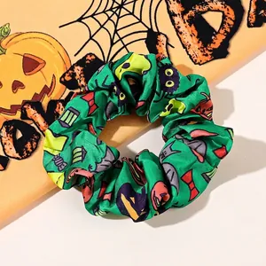 Close-up of green satin scrunchie with pumpkin and spider patterns for Halloween