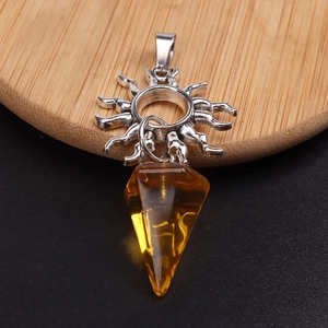 Detalle del colgante de sol plateado y cristal amarillo en forma de cono sobre madera