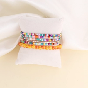 Colorful Bohemian beaded bracelet set displayed on a soft white cushion accessory