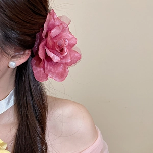 Vue détaillée d'une élégante grande pince à cheveux fleur en maille rose pour femme.