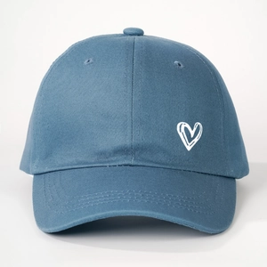 Close-up of the detailed white heart embroidery on the blue cotton baseball cap