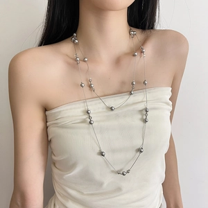 Detail of multi-layered gray pearl necklace on model showing elegant sweater chain style
