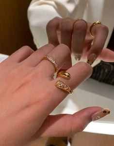Detail showing stacked gold plated rings with teardrop design and colorful zircons