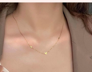 Primer plano de colgantes de corazón en un collar de acero inoxidable dorado en un modelo