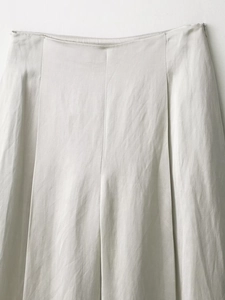 Dettaglio dei pantaloni in lino grigio chiaro con pieghe in vita e grana del tessuto naturale
