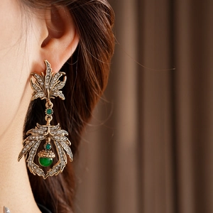 Close-up of vintage gold leaf earrings with rhinestones and a green pendant bead