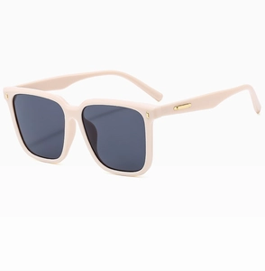 Detail view of cream oversized square sunglasses with gold metal accents and dark lenses