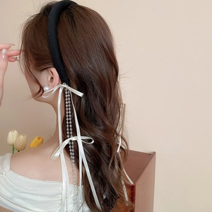 Detail of elegant black velvet headband with white satin bow and cascading crystal beads