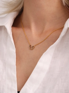 Detail of a gold butterfly necklace with colorful zircon stones on model's neckline