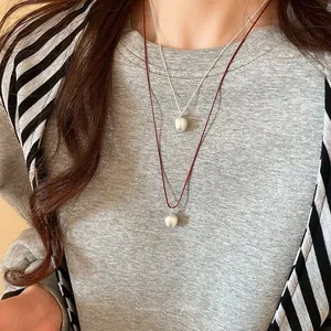 Detail of silver matte apple pendants on red cord and silver chain necklaces