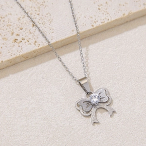 Macro shot of a silver bow necklace with a clear zircon stone on a white stone background