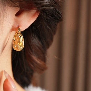 Detailed close-up of 18k gold plated hollow U-shape earring with woven texture pattern