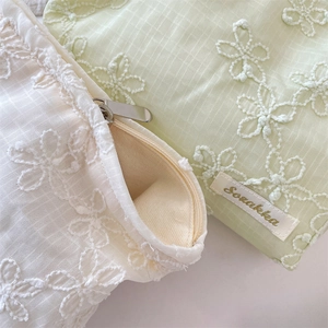Close-up of floral embroidery on plaid fabric cosmetics bags with metal zippers