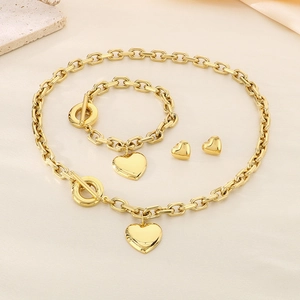 Gold chunky chain jewelry set with heart pendants and T-bar toggles on textured surface