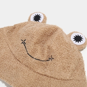 Close-up of camel plush bucket hat featuring cute frog eyes and embroidered smile detail