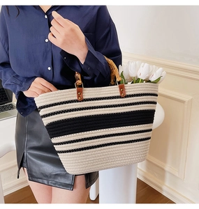 Detail of hand-woven tote bag with black and white stripes and natural bamboo handle