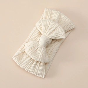 Detail of baby cable knit headband with large bow in off-white soft stretchy nylon fabric