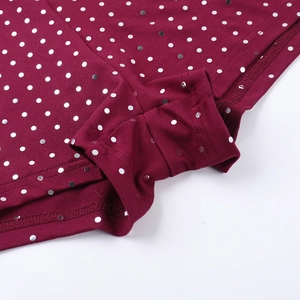 Gros plan sur le tissu bordeaux de la combinaison avec sequins argentés et coutures