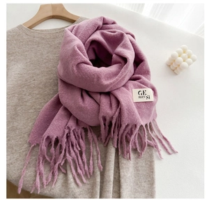 Detail of purple soft cashmere-like scarf with fringe tassels on beige knit sweater