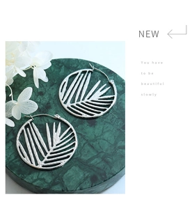 Detailed view of silver titanium steel hoop earrings with cutout bamboo leaf design