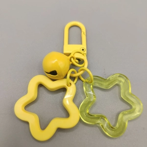 Yellow acrylic star keychain with metal bell and spring clasp on gray background
