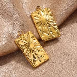Detailed macro of golden rectangular tarot sun pendant with hammer texture on satin