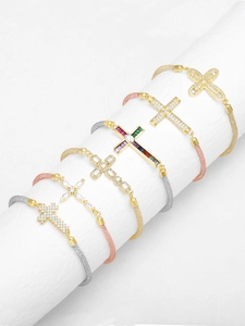 Detalle de pulseras de cruz con malla en oro y plata, decoradas con circonitas de colores