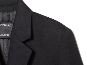 Close-up of black blazer lapel and shoulder seam showing fine twill fabric texture
