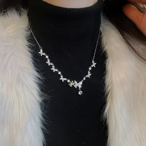 Close-up of silver butterfly necklace with zircon stones on a model wearing black