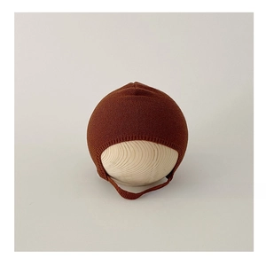 Detailed view of dark brown knitted baby bonnet with soft texture and chin straps