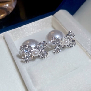 Close-up of elegant silver bow earrings featuring sparkling pavé crystals and white pearls