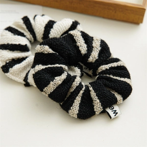 Close-up of two black and white striped tweed scrunchies with soft knitted texture