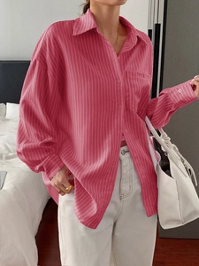 Detail of pink striped loose-fit shirt showing breast pocket and button-down collar design